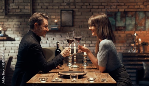 Cheerful couple drinking wine and having romantic dinner at home. Home date night, clinking wine glasses.