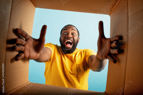 Happy boy receives a package from online shop order. happy and surprised expression. Blue background photo