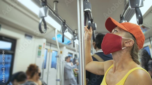 Woman travel caucasian ride at overground train airtrain with wearing protective medical red mask. Girl tourist at airtrain with respirator. Pandemic virus Coronavirus covid-19. People in mask. photo