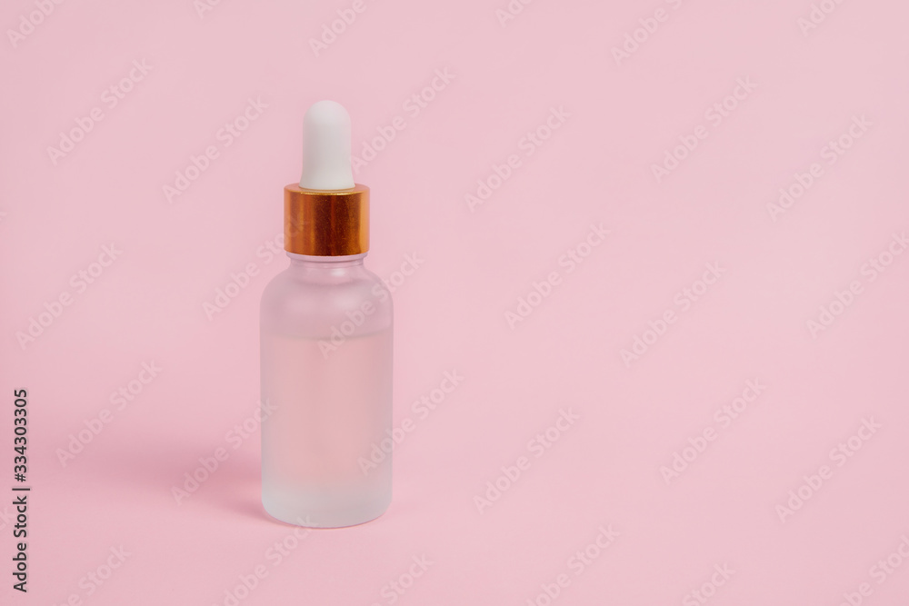 Face care in a glass dropper bottle on a pink background. Skin care concept. Face care in a glass dropper bottle on a pink background. Skin care concept.
