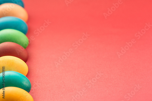 Colorful multi-colored Easter Eggs arranged to left side on a red background photo