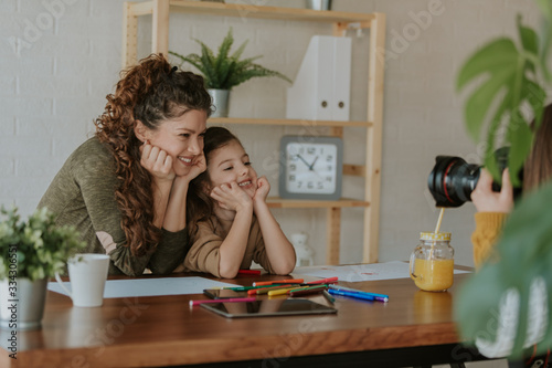 Close photo of happy mother and daughter posing in front of camera at home. Mother and daughter are painting together.