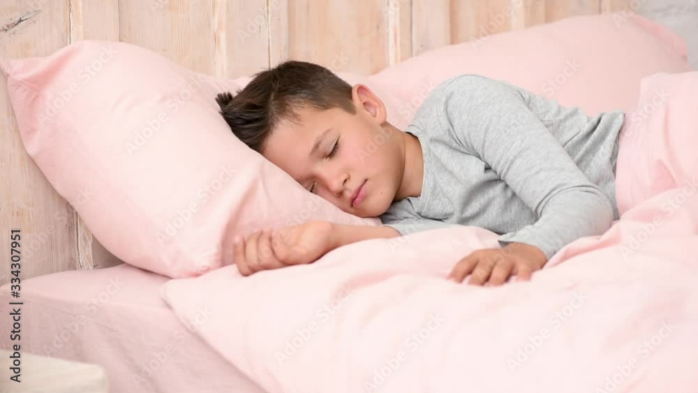 Boy wakes up and smiles in beautiful morning in his bed, children's emotions Boy wakes up and smiles in beautiful morning in his bed, children's emotions