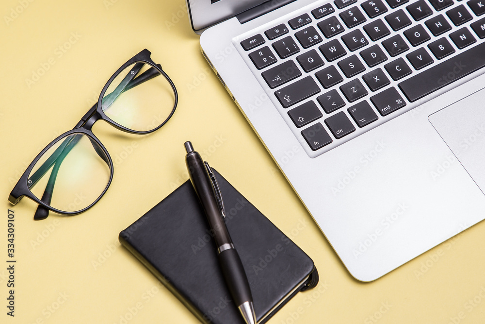 Book, laptop, pen, glasses, yellow background Book, laptop, pen, glasses, yellow background