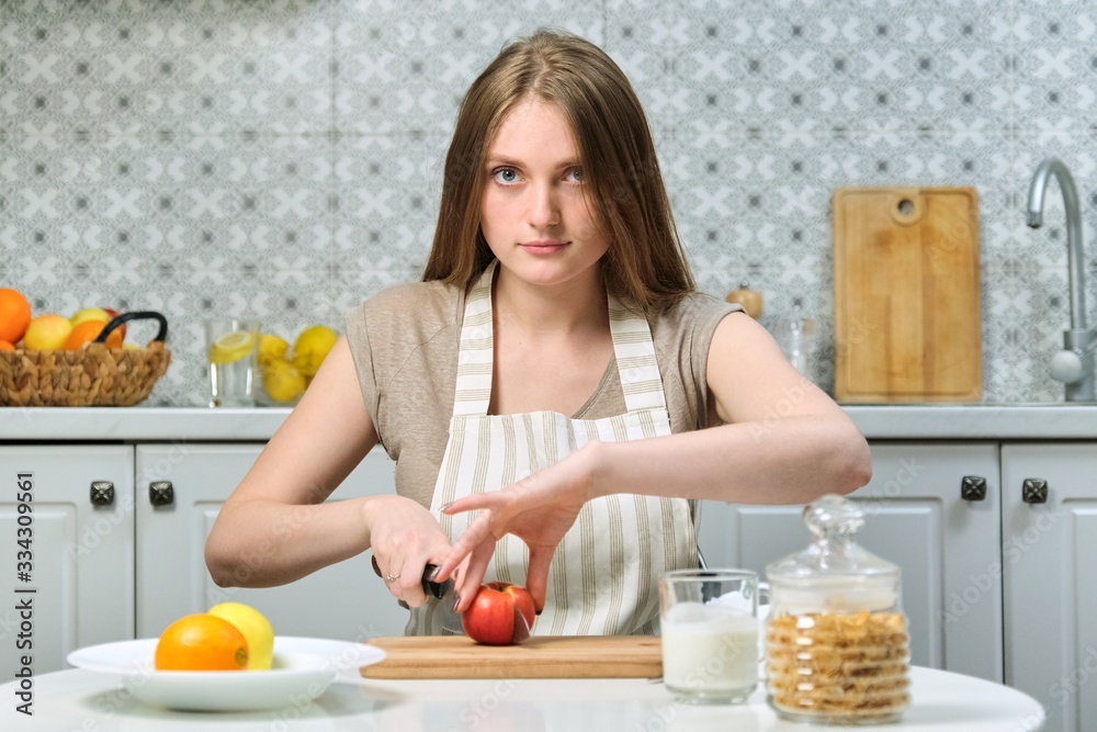 Young beautiful woman with fruits in kitchen, female cutting apples