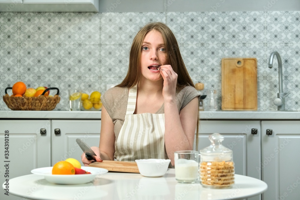 Young woman sitting in kitchen with fruit products knife cutting board