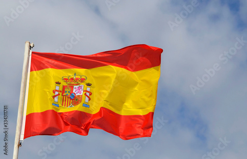 Fluttering flag of Spain.Spanish official flag in the wind against blue cloudy sky. Selective focus.