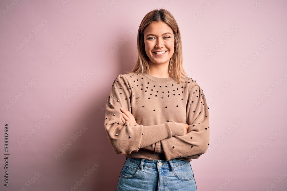 Young beautiful blonde woman wearing fashion sweater over pink isolated background happy face smiling with crossed arms looking at the camera. Positive person. Young beautiful blonde woman wearing fashion sweater over pink isolated background happy face smiling with crossed arms looking at the camera. Positive person.