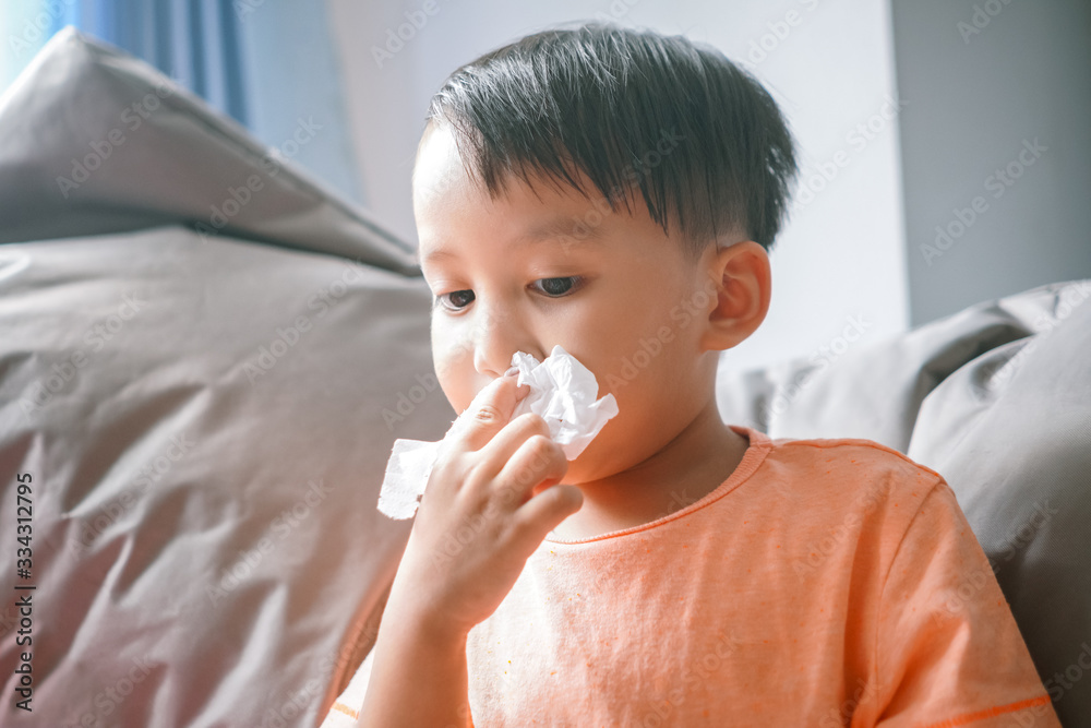 Asian boy wiping his nose with tissues paper Asian boy wiping his nose with tissues paper