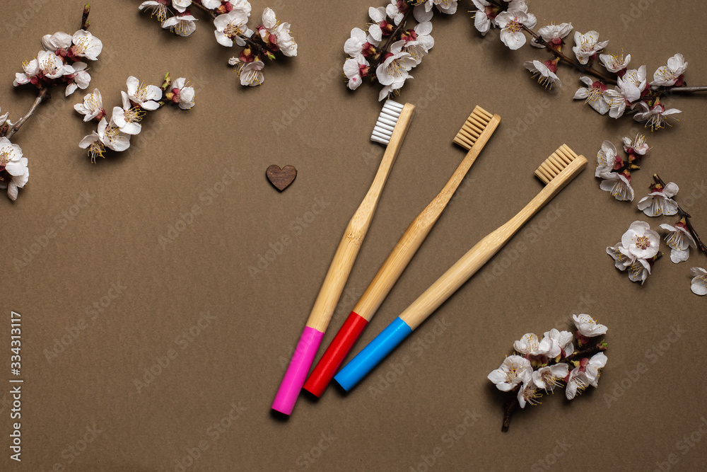 Three natural bamboo toothbrushes and a wooden heart on a brown background. Three natural bamboo toothbrushes and a wooden heart on a brown background.