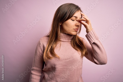 Beautiful young woman wearing turtleneck sweater over pink isolated background tired rubbing nose and eyes feeling fatigue and headache. Stress and frustration concept.