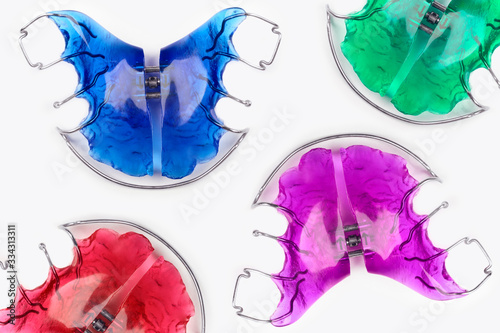 Close-up of children's orthodontic appliances in bright, fun colours on a white table. Concept of oral health in childhood.