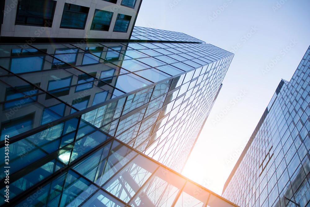 Obraz premium Skyscraper, modern building in the city with sunlight. Glass wall of an office building in the sunlight. Office building window close up with sunrise, reflection and perspective.