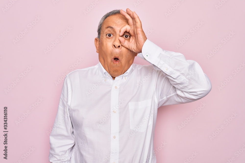 Senior handsome grey-haired man wearing elegant shirt over isolated pink background doing ok gesture shocked with surprised face, eye looking through fingers. Unbelieving expression. Senior handsome grey-haired man wearing elegant shirt over isolated pink background doing ok gesture shocked with surprised face, eye looking through fingers. Unbelieving expression.