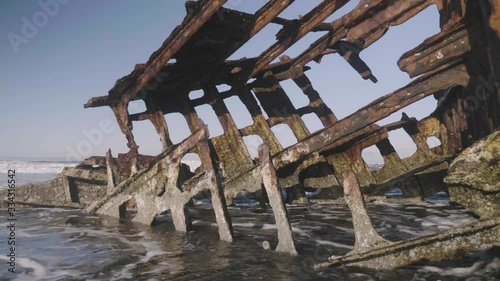 Peter Iredale rusty shipwreck at fort stevens state park astoria oregon ocean waves and blue sky on sandy beach close up reveal slow motion