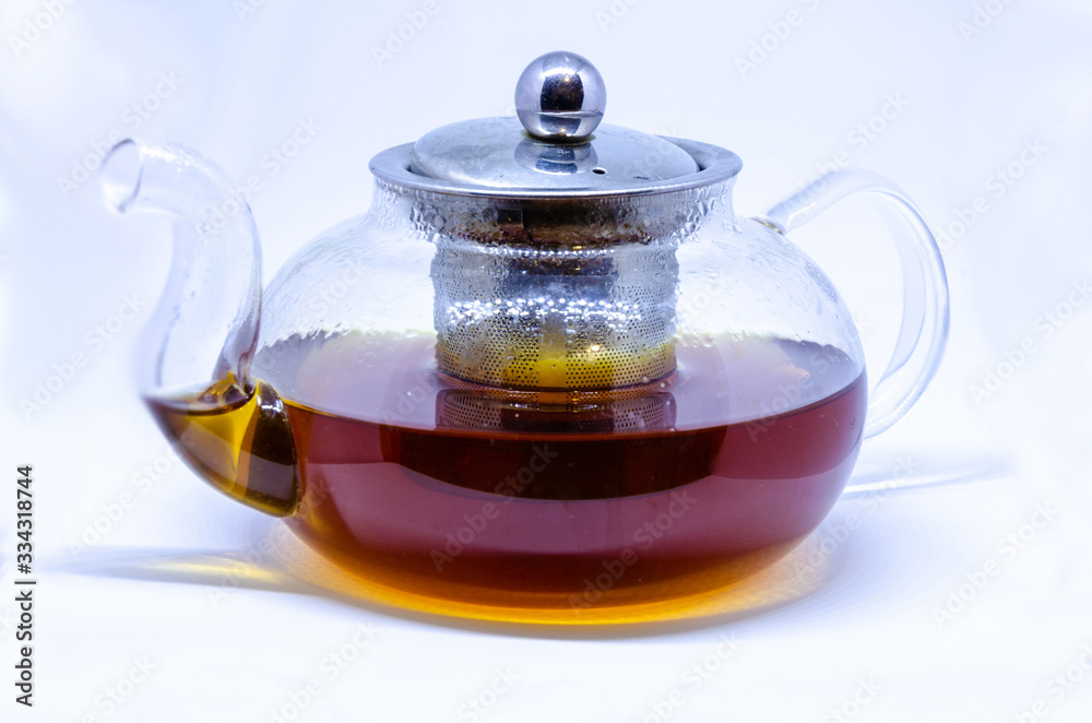 A glass tea pot with tea isolated on a white background. A glass tea pot with tea isolated on a white background.