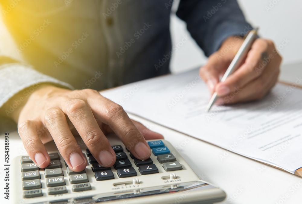 Fototapeta premium Businessman writing on notebook using calculator