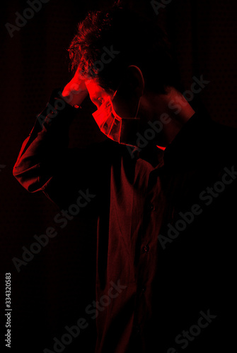 masked doctor in a dark room with red light