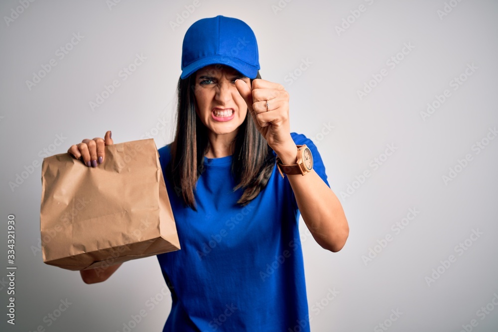 Young delivery woman with blue eyes wearing cap holding paper bag with food annoyed and frustrated shouting with anger, crazy and yelling with raised hand, anger concept Young delivery woman with blue eyes wearing cap holding paper bag with food annoyed and frustrated shouting with anger, crazy and yelling with raised hand, anger concept