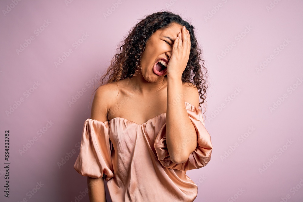 Young beautiful woman with curly hair wearing casual t-shirt standing over pink background Yawning tired covering half face, eye and mouth with hand. Face hurts in pain. Young beautiful woman with curly hair wearing casual t-shirt standing over pink background Yawning tired covering half face, eye and mouth with hand. Face hurts in pain.