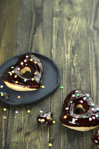 donuts with chocolate glaze on a black wooden table, home made donuts, donuts and chocolate chips © Ana