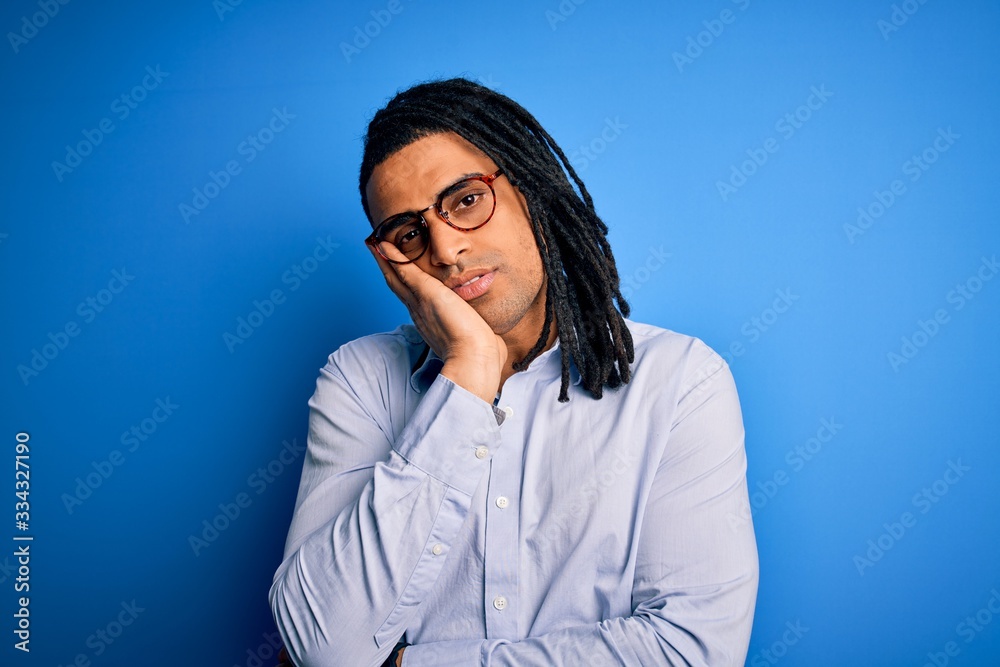 Young handsome african american man with dreadlocks wearing casual shirt and glasses thinking looking tired and bored with depression problems with crossed arms.
