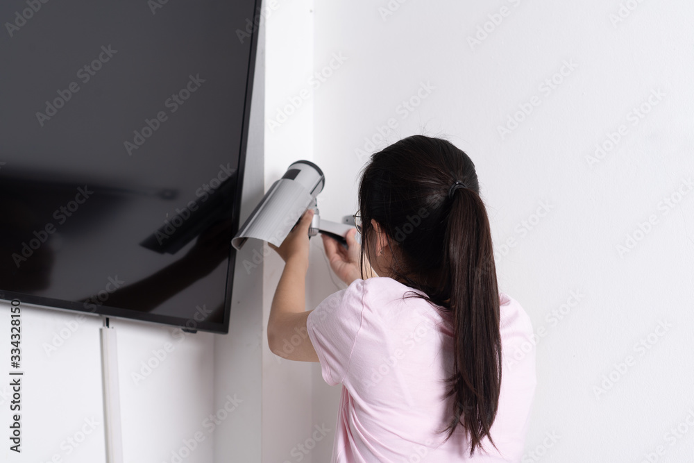 Close up woman setting up security camera security at home.