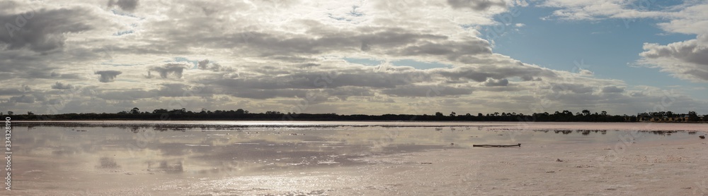 panorama of pink salt lake near Horsham, rural Victoria stretching out under a cloud filled sky reflecting in the lakes water, Australia