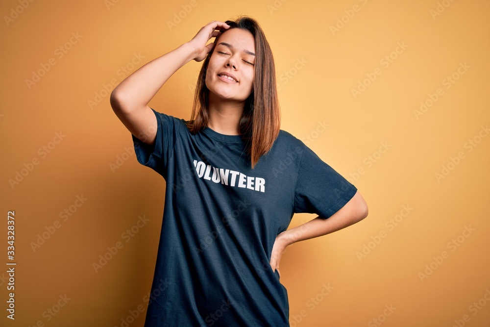 Young beautiful brunette girl doing volunteering wearing t-shirt with volunteer message word smiling confident touching hair with hand up gesture, posing attractive and fashionable Young beautiful brunette girl doing volunteering wearing t-shirt with volunteer message word smiling confident touching hair with hand up gesture, posing attractive and fashionable
