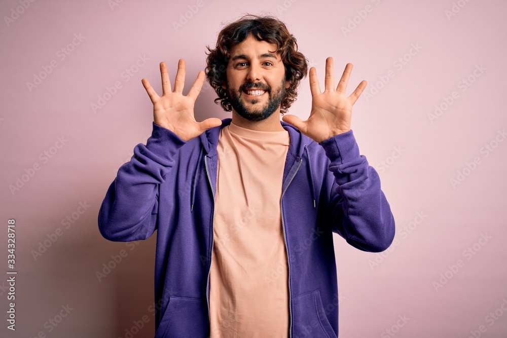 Young handsome sporty man with beard wearing casual sweatshirt over pink background showing and pointing up with fingers number ten while smiling confident and happy. Young handsome sporty man with beard wearing casual sweatshirt over pink background showing and pointing up with fingers number ten while smiling confident and happy.