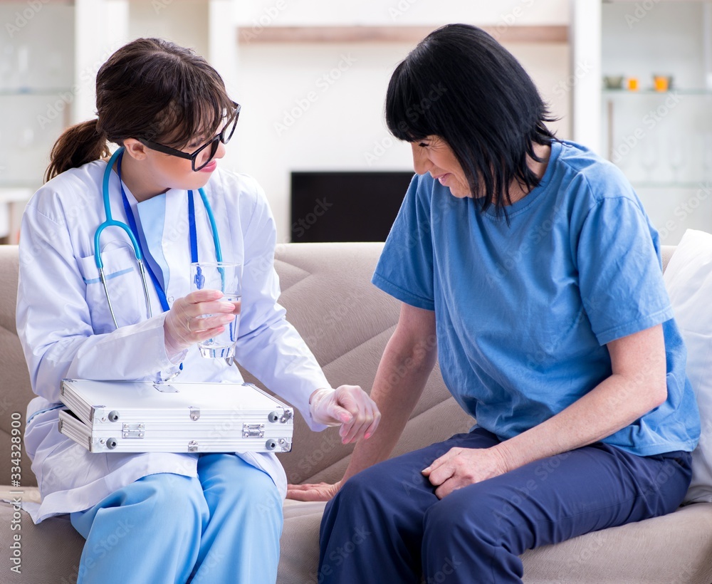 Fototapeta premium Young doctor visiting old mature woman for check-up