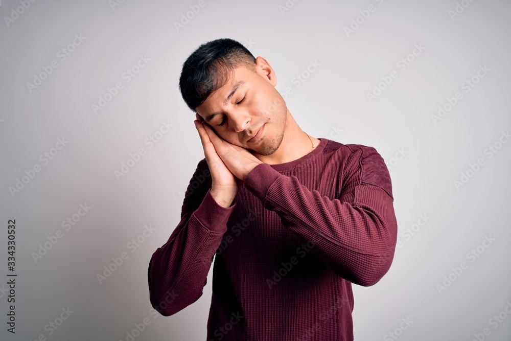 Young handsome hispanic man wearing casual shirt standing over white isolated background sleeping tired dreaming and posing with hands together while smiling with closed eyes. Young handsome hispanic man wearing casual shirt standing over white isolated background sleeping tired dreaming and posing with hands together while smiling with closed eyes.