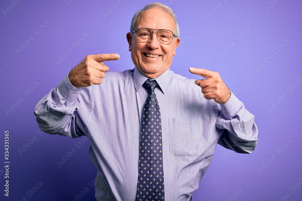 Grey haired senior business man wearing glasses standing over purple isolated background smiling cheerful showing and pointing with fingers teeth and mouth. Dental health concept. Grey haired senior business man wearing glasses standing over purple isolated background smiling cheerful showing and pointing with fingers teeth and mouth. Dental health concept.