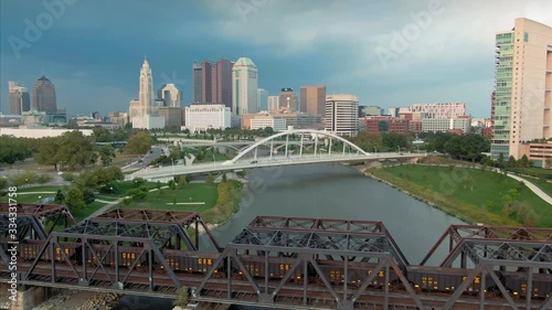 Aerial: Train crossing bridge on the Scioto River and downtown Columbus, Ohio, USA. 20 September 2019