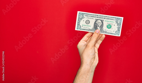 Beautiful hand of man holding one dollar banknote over isolated red background