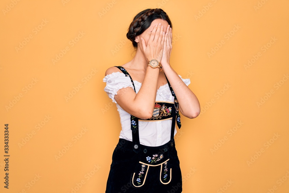 Young beautiful german woman with blue eyes wearing traditional octoberfest dress with sad expression covering face with hands while crying. Depression concept. Young beautiful german woman with blue eyes wearing traditional octoberfest dress with sad expression covering face with hands while crying. Depression concept.