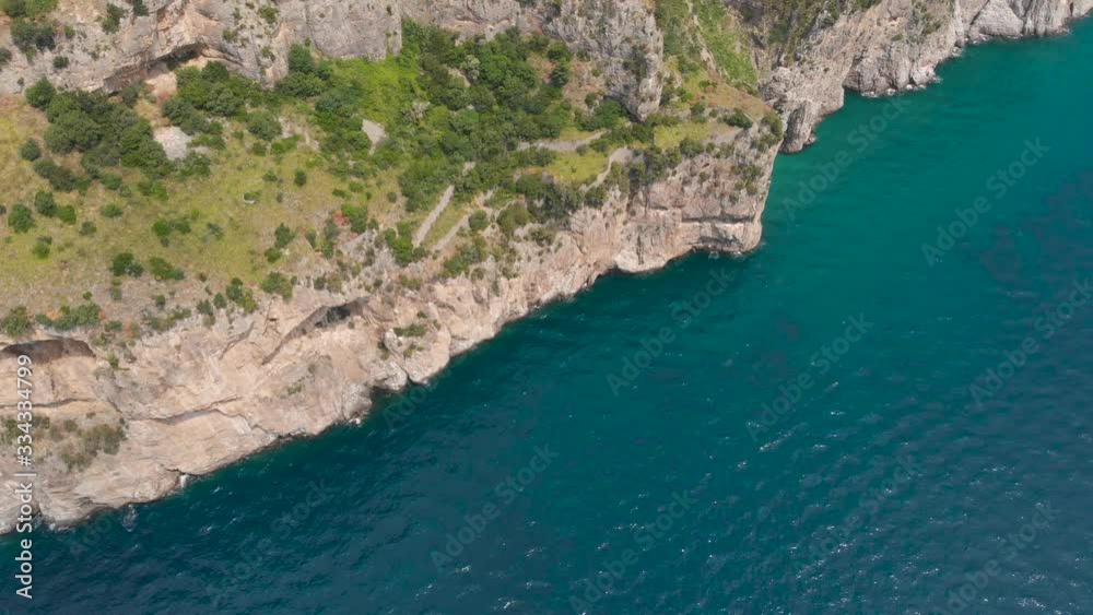 Aerial drone top view flying above crystal clear sea waters to colorful trees on top of rocky cliffs Aerial drone top view flying above crystal clear sea waters to colorful trees on top of rocky cliffs