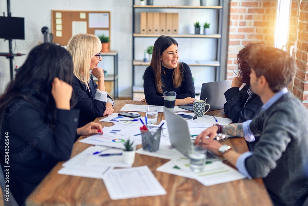 Group of business workers smiling happy and confident. Working together with smile on face using laptop and speaking at the office Group of business workers smiling happy and confident. Working together with smile on face using laptop and speaking at the office