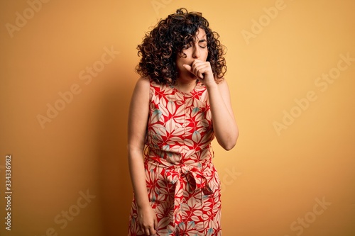 Young beautiful curly arab woman on vacation wearing summer floral dress and sunglasses feeling unwell and coughing as symptom for cold or bronchitis. Health care concept.