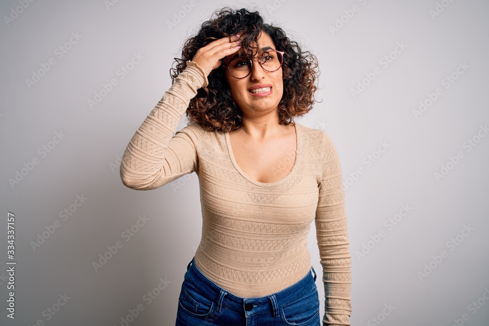 Young beautiful curly arab woman wearing casual t-shirt and glasses over white background worried and stressed about a problem with hand on forehead, nervous and anxious for crisis Young beautiful curly arab woman wearing casual t-shirt and glasses over white background worried and stressed about a problem with hand on forehead, nervous and anxious for crisis