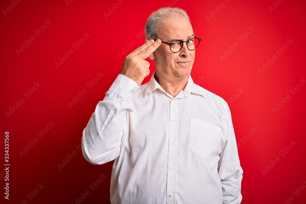 Middle age handsome hoary man wearing casual shirt and glasses over red background Shooting and killing oneself pointing hand and fingers to head like gun, suicide gesture. Middle age handsome hoary man wearing casual shirt and glasses over red background Shooting and killing oneself pointing hand and fingers to head like gun, suicide gesture.