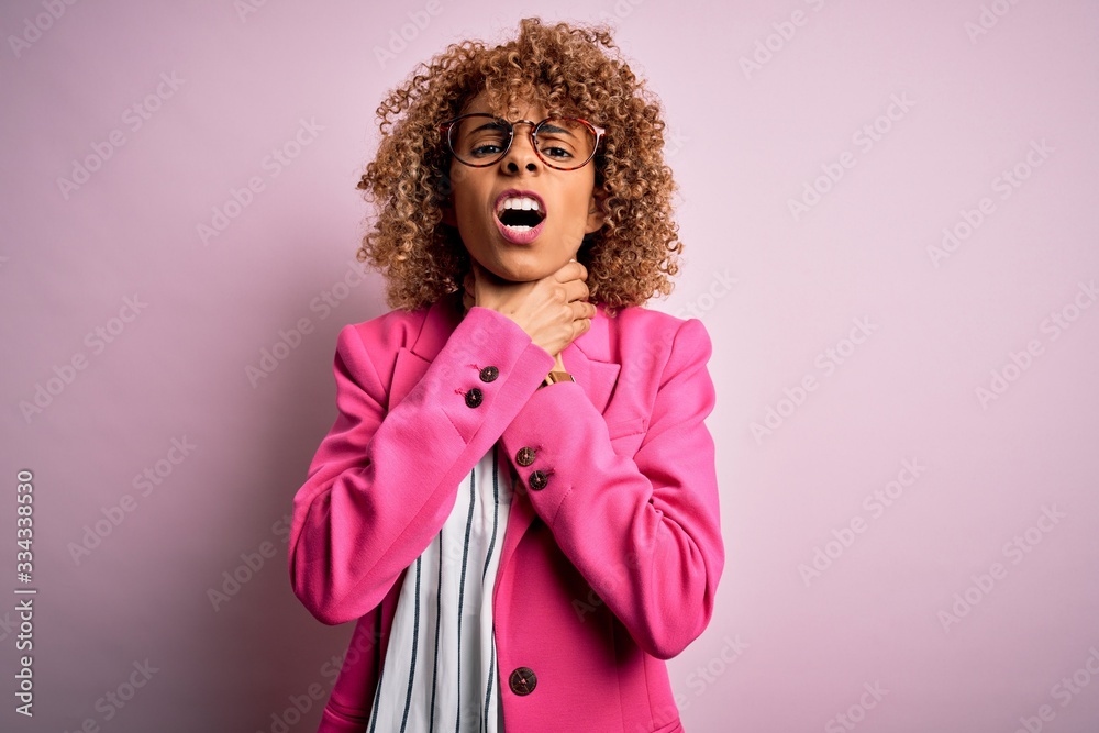 Young african american businesswoman wearing glasses standing over pink background shouting suffocate because painful strangle. Health problem. Asphyxiate and suicide concept.