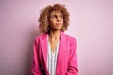 Young african american businesswoman wearing glasses standing over pink background smiling looking to the side and staring away thinking.
