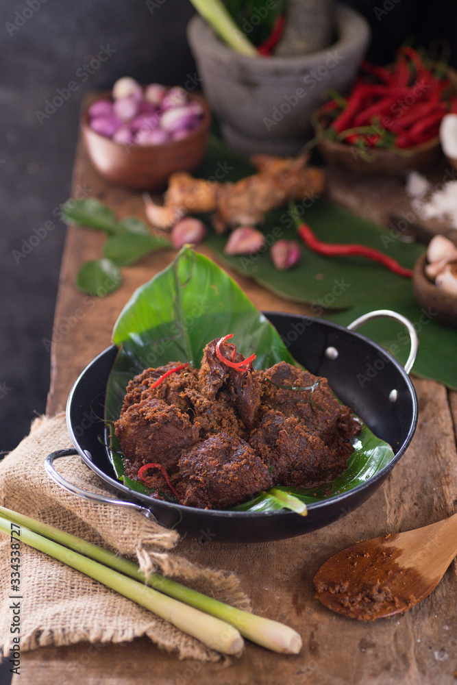 Rendang is a traditional dish shared from Malaysia and Indonesia, commonly served during eid celebration. Made of coconut milk, meat, and spices. Served in wok on wooden table. Rendang is a traditional dish shared from Malaysia and Indonesia, commonly served during eid celebration. Made of coconut milk, meat, and spices. Served in wok on wooden table.