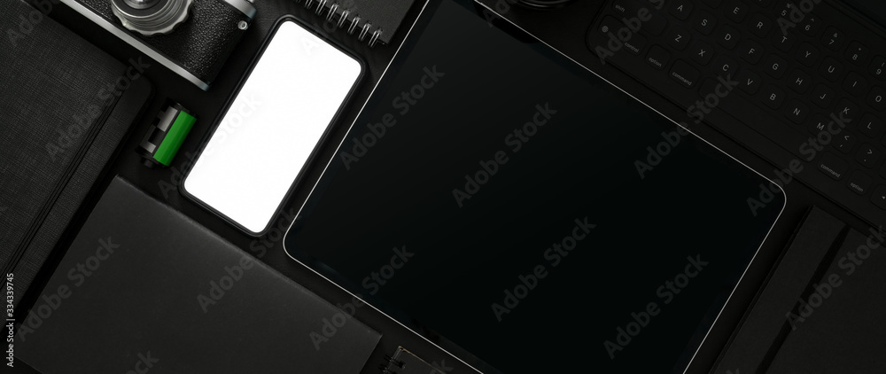 Top view of dark workspace with mock-up smartphone, tablet and photographer supplies Top view of dark workspace with mock-up smartphone, tablet and photographer supplies