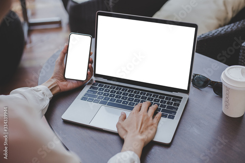 mockup image blank screen computer,cell phone with white background for advertising text,hand woman using laptop texting mobile contact business search information on desk in cafe.marketing,design