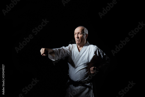 The old athlete trains a punch on a black background
