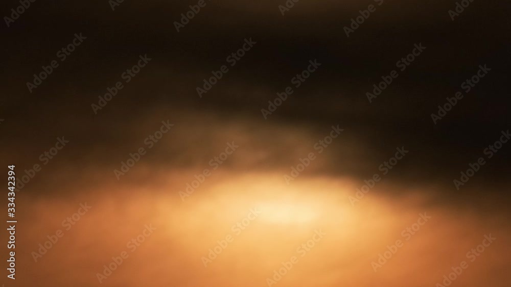 Close up of orange and round sun in the morning rising behind clouds timelapse Close up of orange and round sun in the morning rising behind clouds timelapse