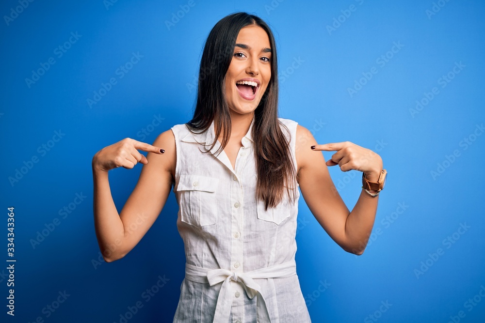 Young beautiful brunette woman wearing casual dress over isolated blue background looking confident with smile on face, pointing oneself with fingers proud and happy. Young beautiful brunette woman wearing casual dress over isolated blue background looking confident with smile on face, pointing oneself with fingers proud and happy.