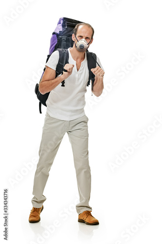 young man with backpack walking in protective mask on white background